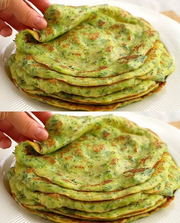 Plate of golden-brown zucchini pancakes topped with fresh herbs