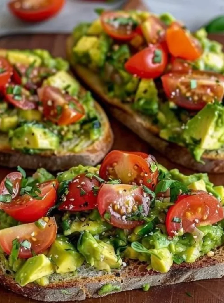 Sliced avocado bread topped with fresh tomatoes on a wooden table