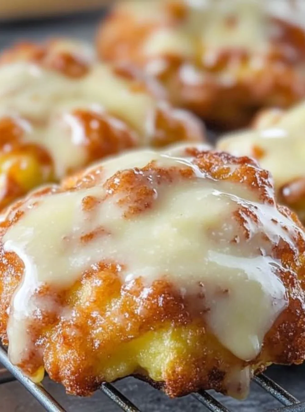 Freshly baked apple fritters topped with icing and cinnamon sugar.