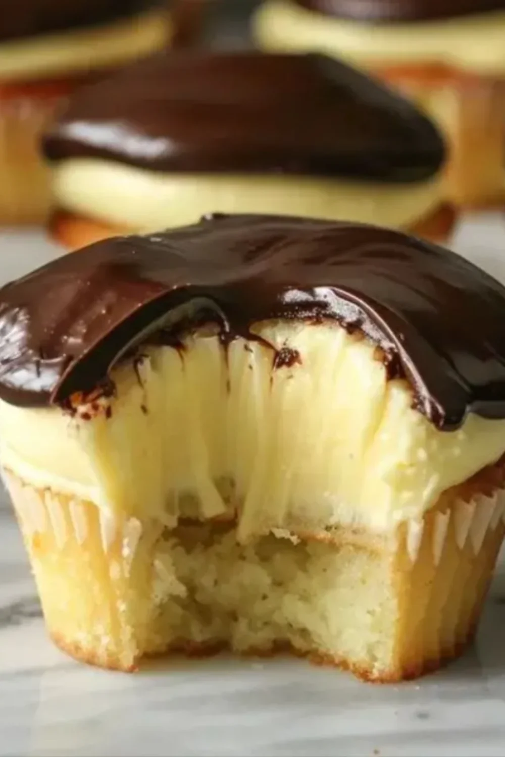 Delicious Boston Cream Pie Cupcakes topped with chocolate ganache and cream filling