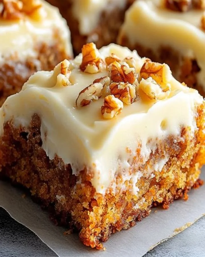 Decadent carrot cake bars with cream cheese frosting on a plate