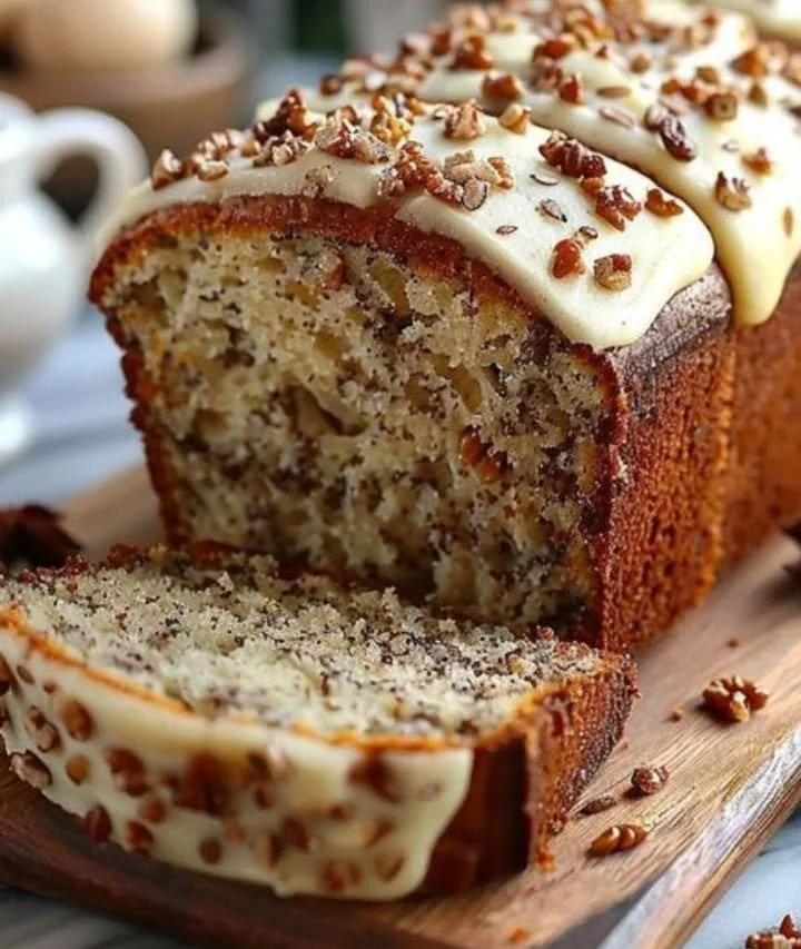 Delicious Hummingbird Bread with cinnamon cream cheese frosting on a rustic wooden table.